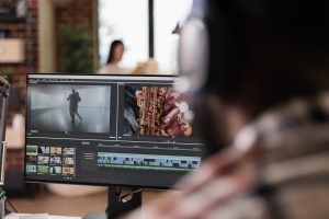 Young freelancer editing footage on software, working to edit video montage with color grading and audio effects. Sound and film production content, making creative movie on computer.