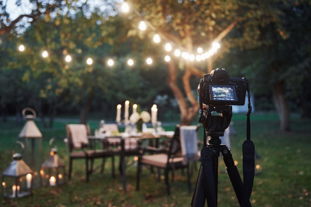 Professional equipment. Camera on the tripod stand in the field in front of prepared table at evening time.